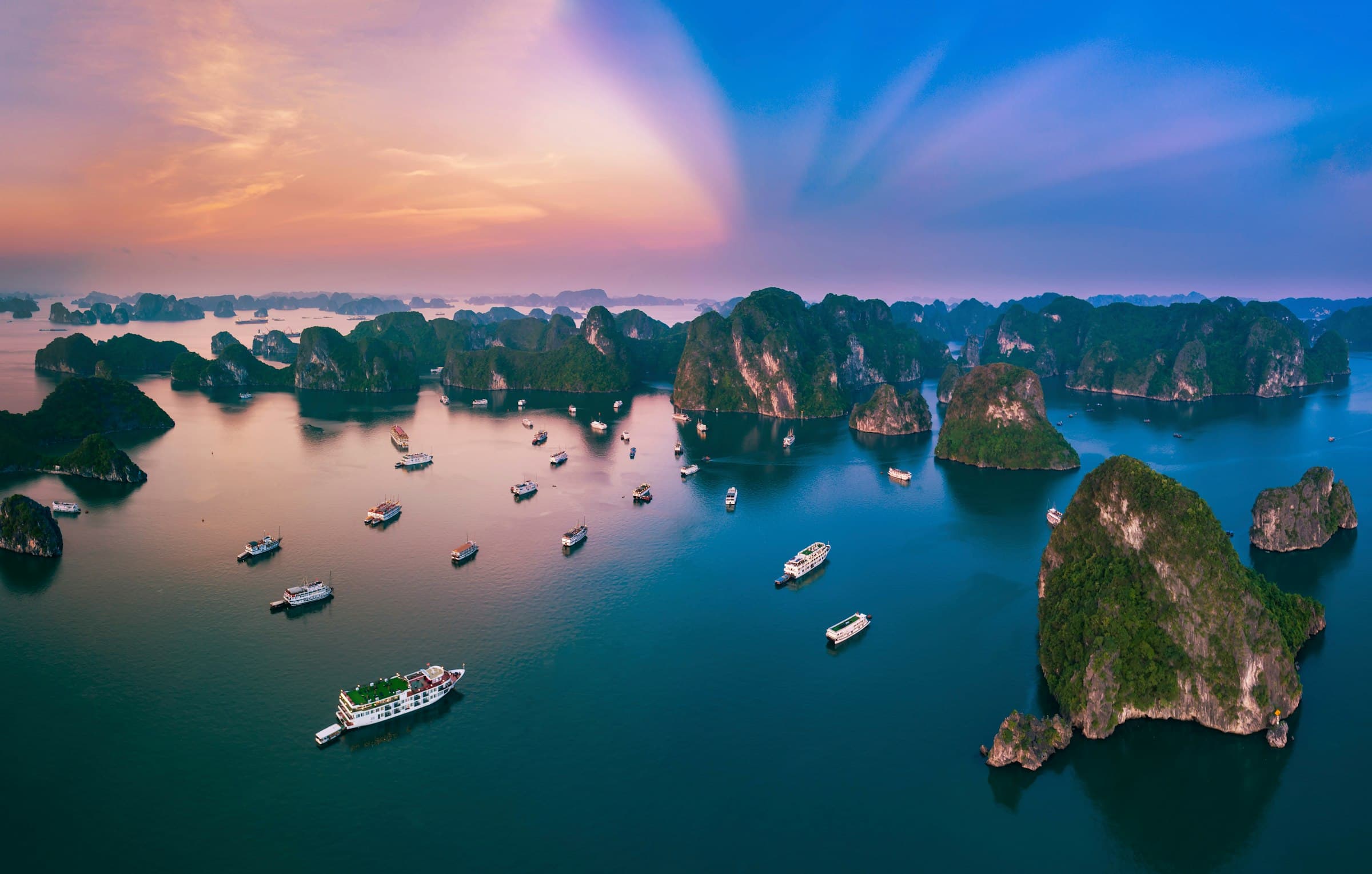 Limestone islands and cruise boats in Halong Bay at dusk