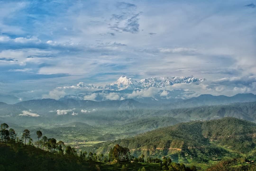 Snow-capped Himalayan peaks above forested hills in Uttarakhand