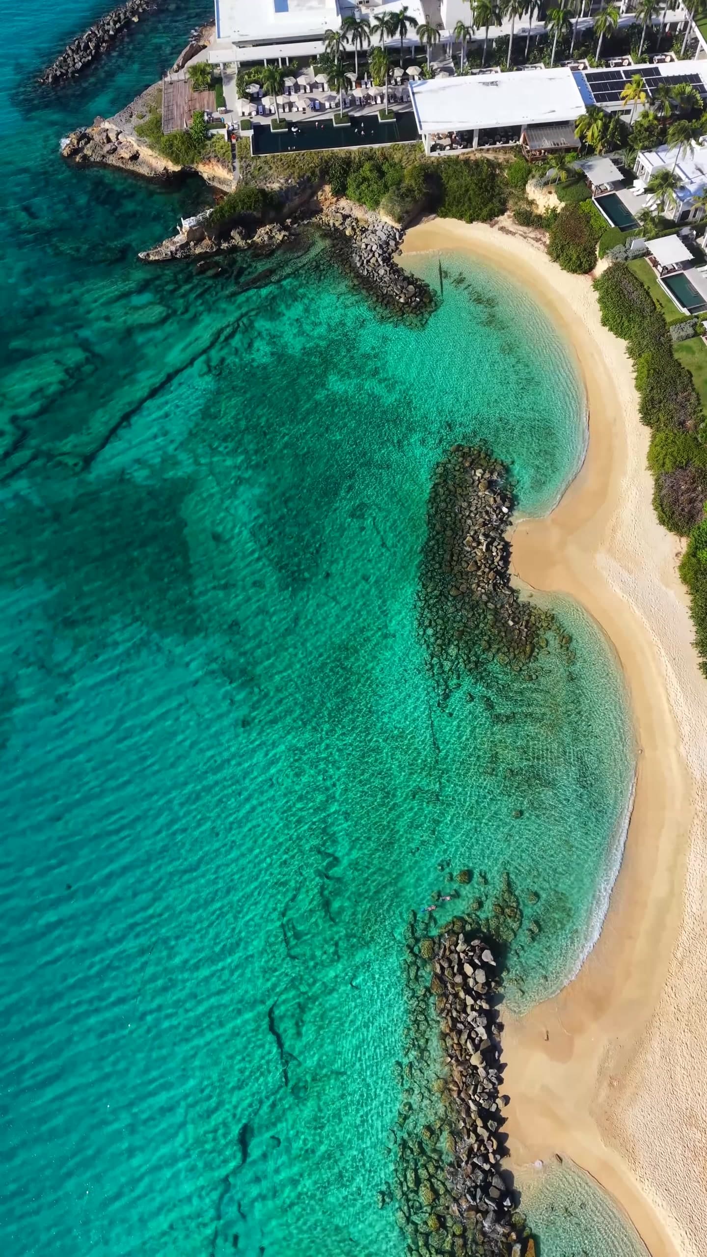 Aerial view of a turquoise bay and a curving sandy beach