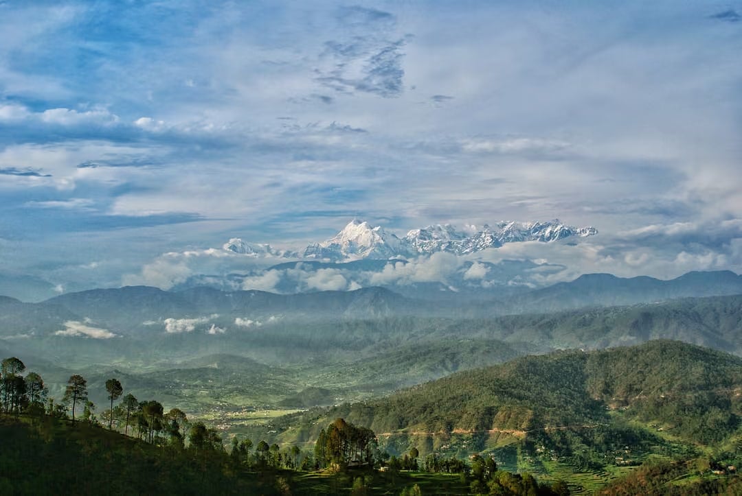 Snow-capped Himalayan peaks above forested hills in Uttarakhand