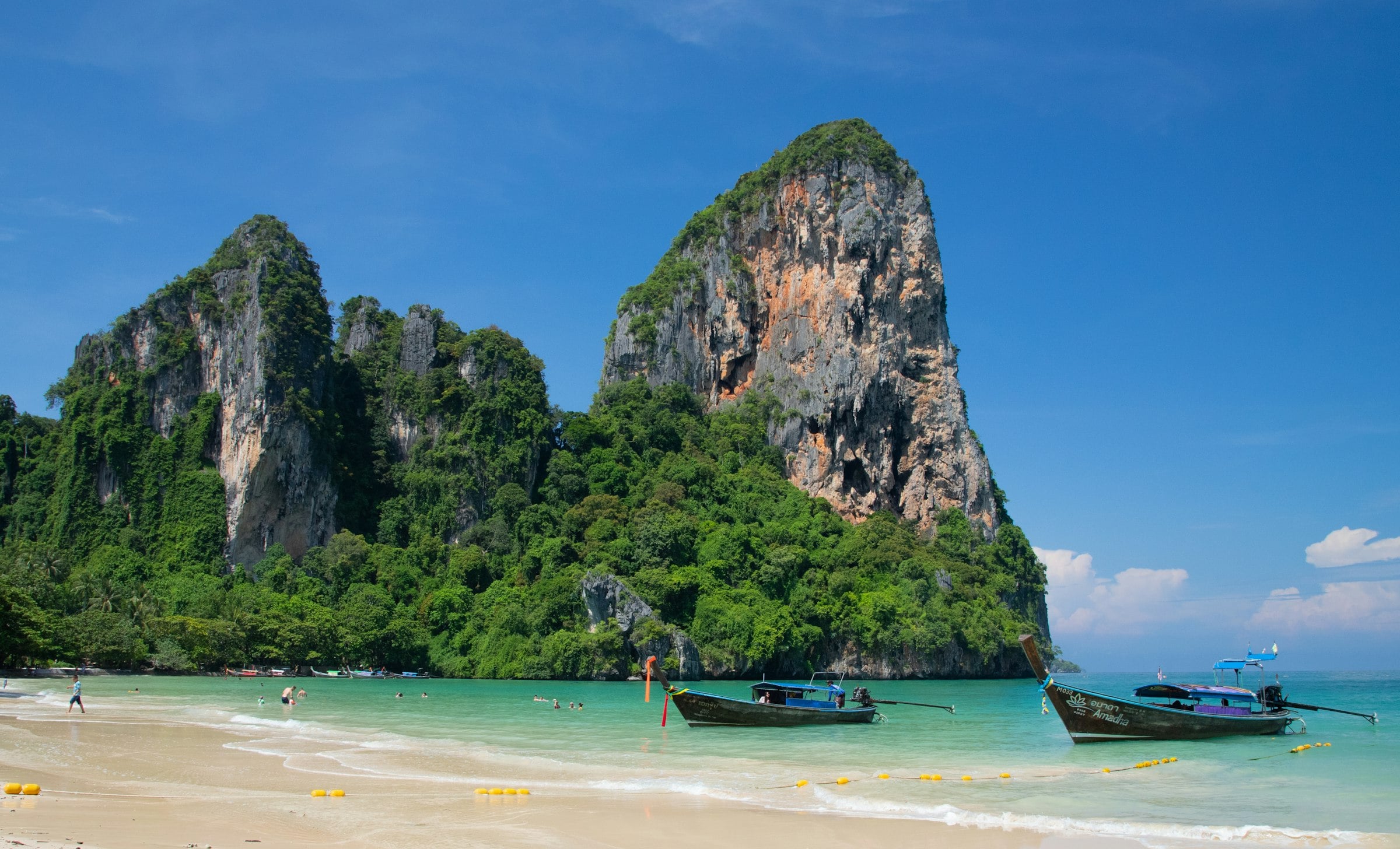 Longtail boats below the limestone cliffs of Railay Beach in Krabi